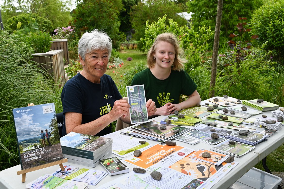 Deux volontaires, une jeune et une plus âgée, sont assises à une table remplie de flyers sur divers sujets naturalistes. Toute sourire, elles sont prêtes à accueillir les personnes désireuses de s'informer.